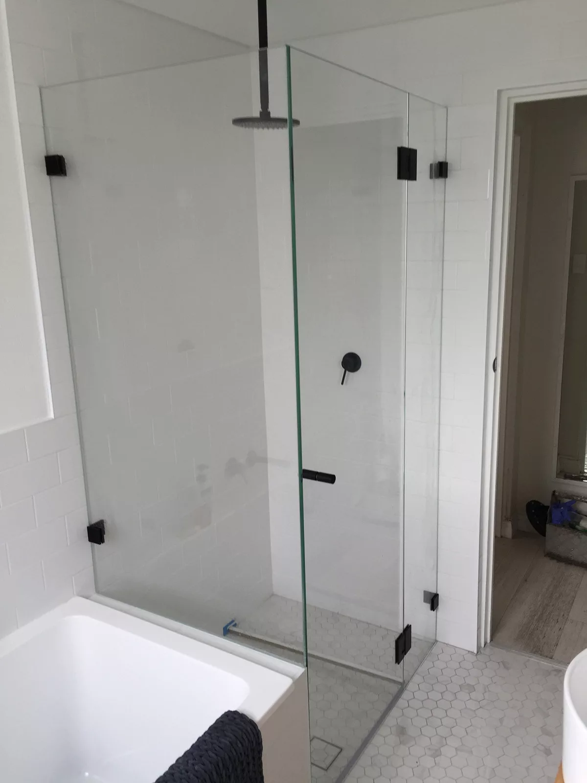 Frameless corner shower screen over bath